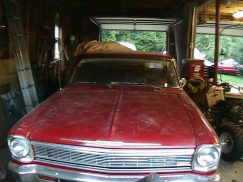 1966 Chevrolet Nova - A red 1966 Chevrolet Nova sits in a garage, showing its front grille and headlights.
