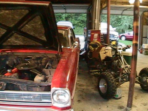 1966 Chevrolet Nova - A red 1966 Chevrolet Nova is parked in a garage with its hood up, next to an ATV and other equipment.