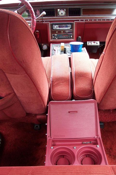 1985 Ford Crown Victoria LTD - Interior view of a car plush red seats, a wood-grain dashboard, and a prominent center console with cup holders.