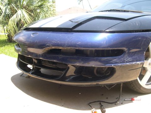 1997 Ford Probe - Front view of a blue car bumper with visible scratches and damage, and racing stripes on the hood.