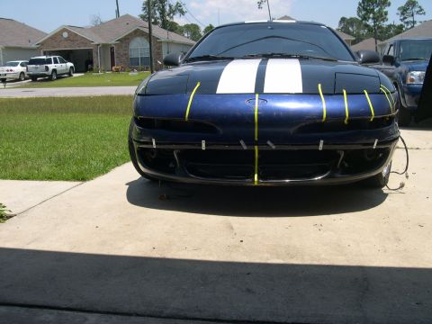 1997 Ford Probe - Front view of a blue car with yellow tape on the bumper and white stripes on the hood.