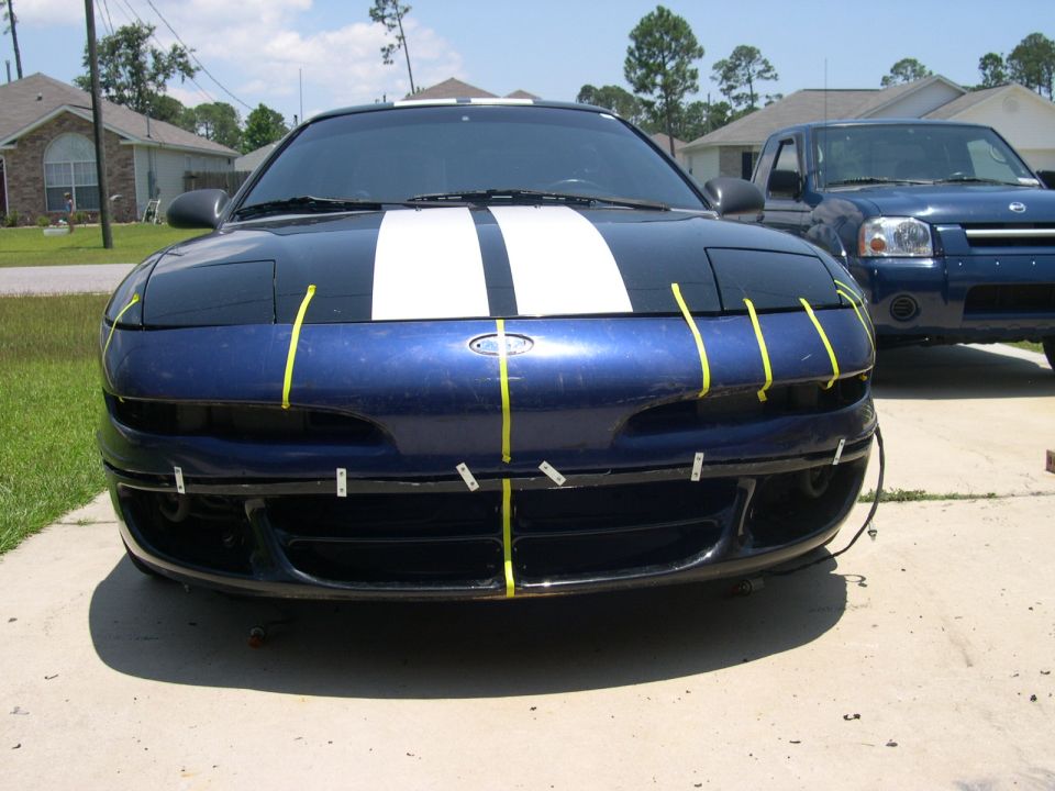 1997 Ford Probe front end with blue paint, white racing stripes, and yellow tape on the bumper