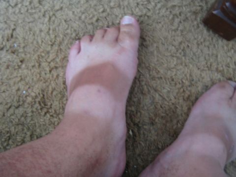 1968 Ford Mustang - Tan lines are visible on feet resting on a textured brown carpet.