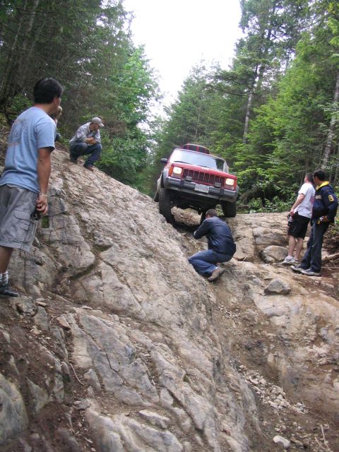 2000 Jeep Cherokee - Jeep Cherokee navigates a challenging off-road obstacle with onlookers present.
