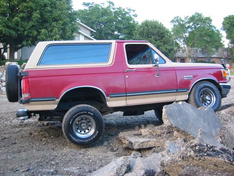 1990 Ford Bronco - This Ford Bronco is shown from the side, navigating a rocky terrain.