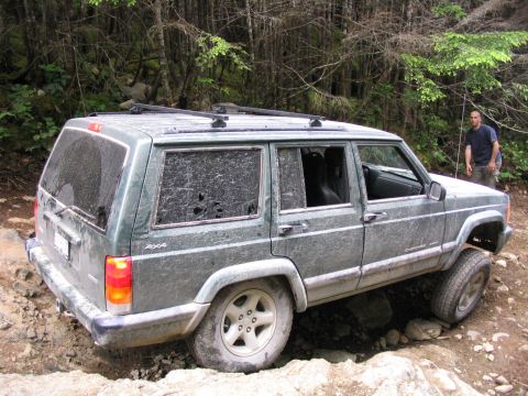 2000 Jeep Cherokee - Jeep Cherokee navigating a challenging rocky trail with a person observing.