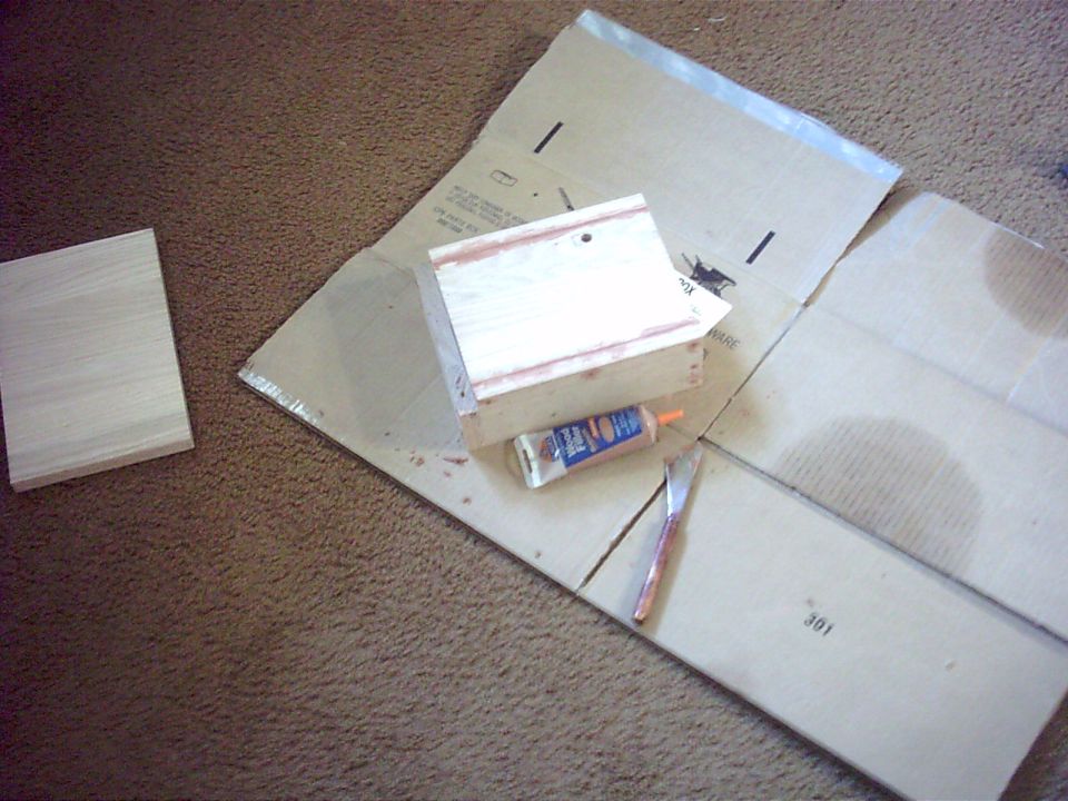 Wood pieces, tube of glue, and a knife on cardboard