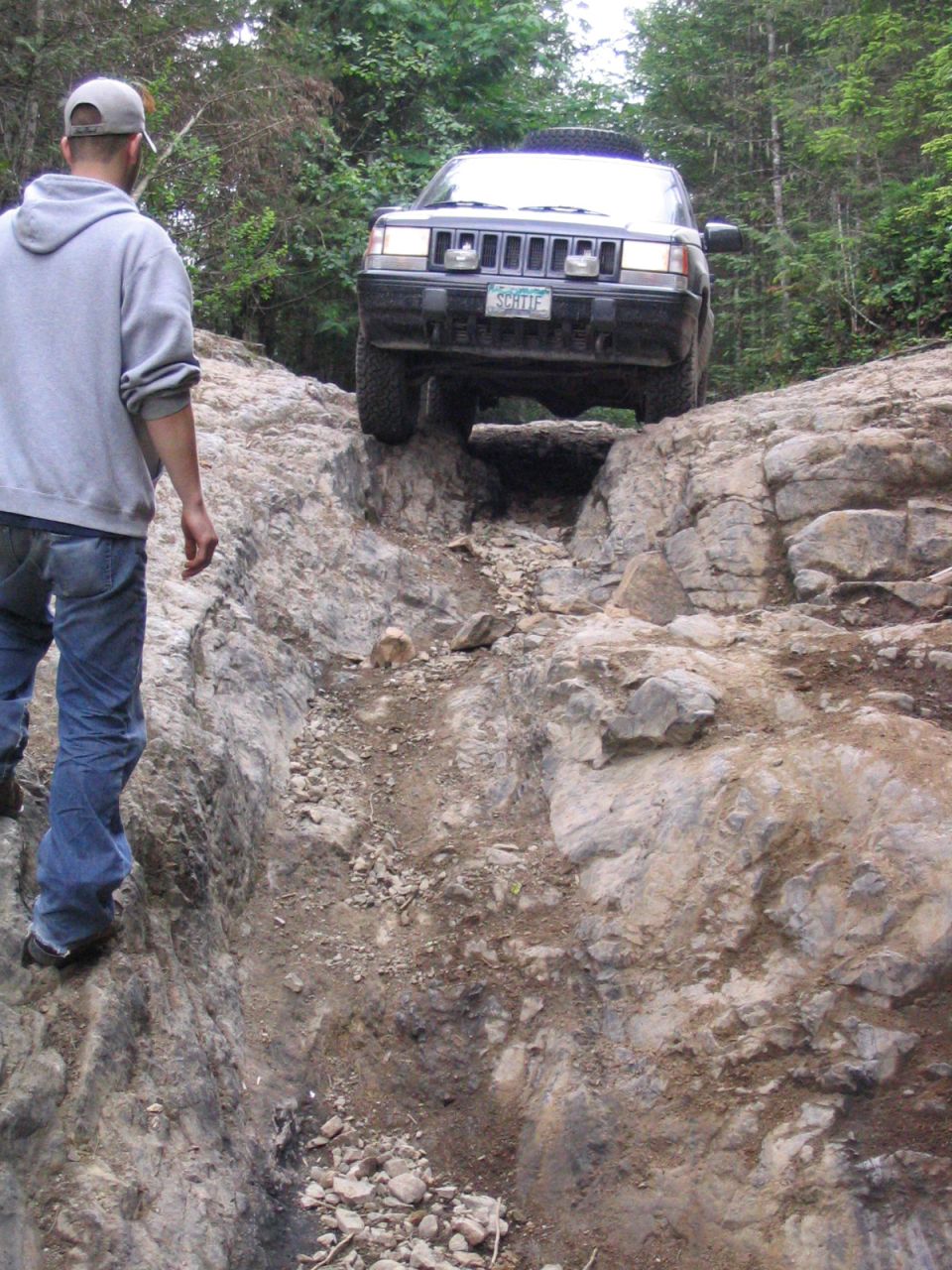 Dark colored Jeep Grand Cherokee navigating a rocky off-road trail, front view