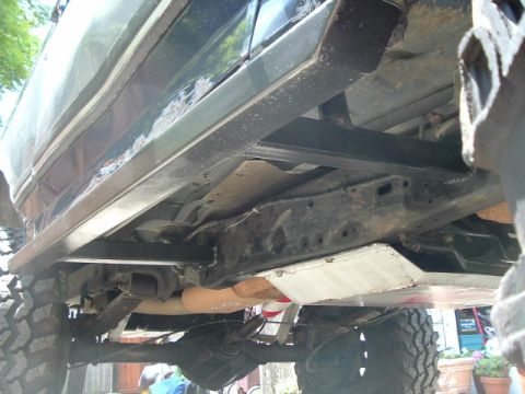 1989 Ford Bronco - The undercarriage of an SUV shows modifications including skid plates and off-road tires.