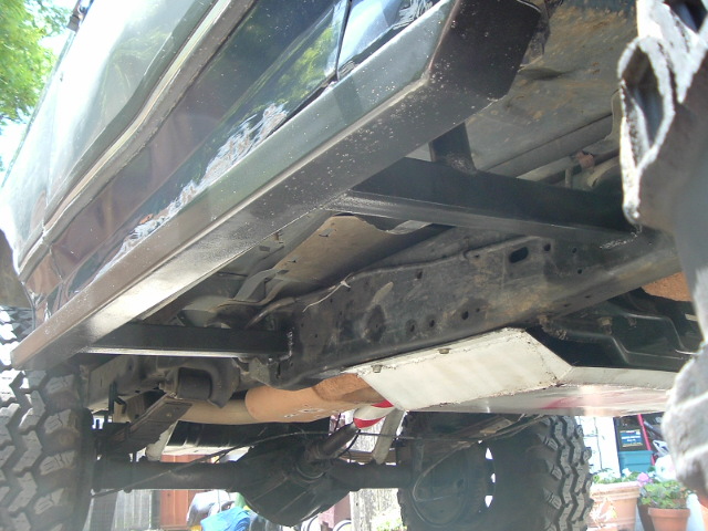 Undercarriage of a Ford Bronco showing frame, driveshaft and off-road tires