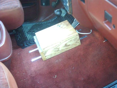 1990 Ford Bronco - A wooden block is placed on the floor mat inside a vehicle's interior.