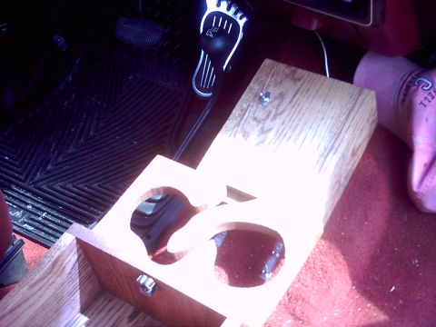1990 Ford Bronco - A custom wooden cup holder with two openings is shown installed on the floor of a vehicle's interior.
