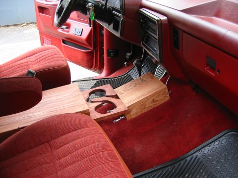1990 Ford Bronco - The interior of the vehicle features red upholstery and a custom-made wooden console with integrated cup holders.