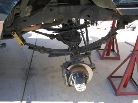 1994 Ford Bronco - Close-up view of the rear suspension and axle of a vehicle undergoing maintenance.