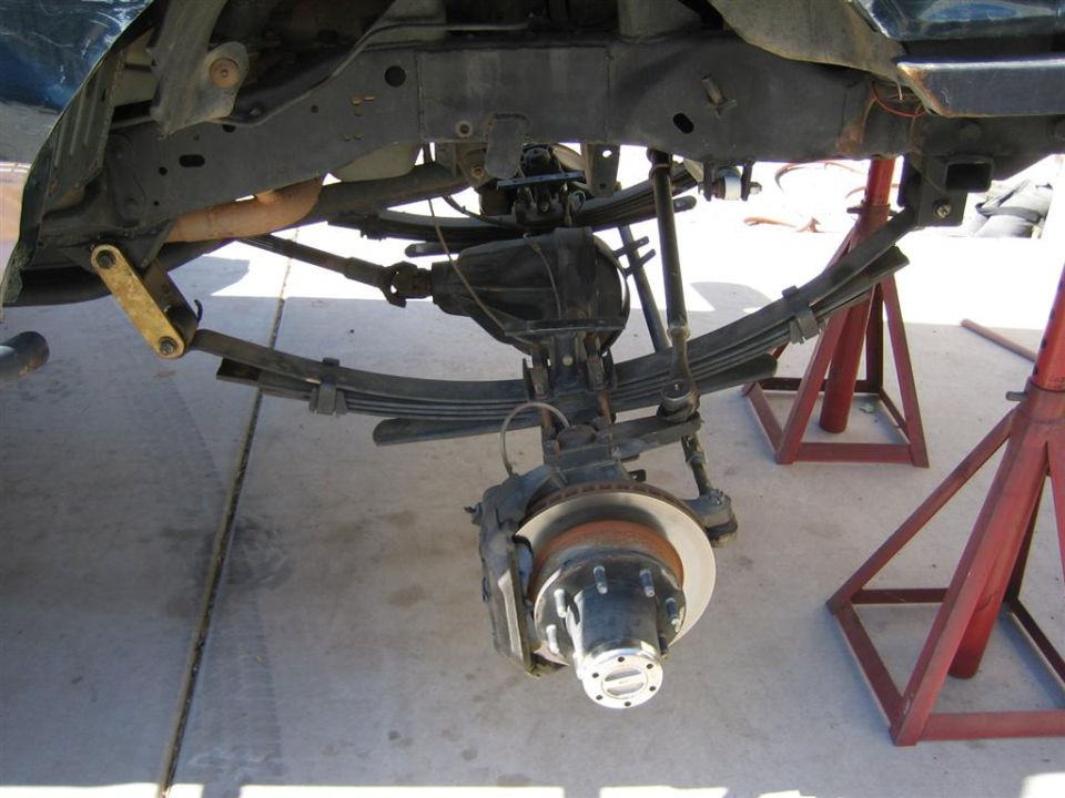 Leaf-sprung solid front axle with wheel removed, showing rotor, caliper and 8-lug hub