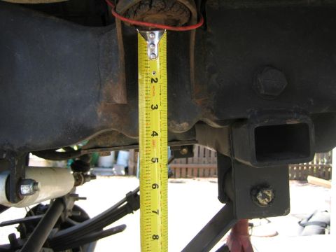 1994 Ford Bronco - A tape measure is used to gauge the distance between the vehicle's frame and suspension components.