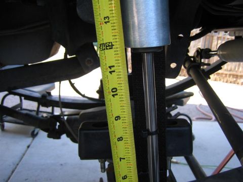 1994 Ford Bronco - A tape measure is used to measure the length of a vehicle's shock absorber, indicating a suspension component measurement.