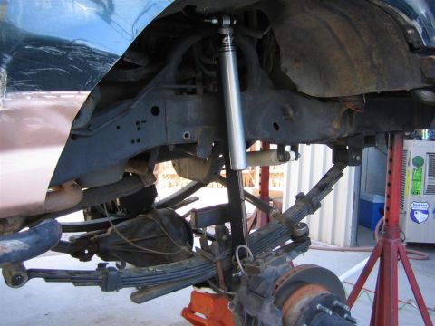 1994 Ford Bronco - Undercarriage view of a vehicle's suspension system, showing leaf springs and a shock absorber.