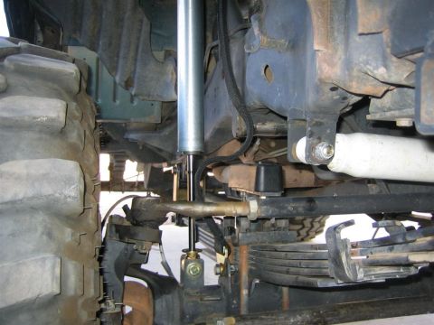 1994 Ford Bronco - Detailed view of the suspension system and a large tire, showing the shock absorber and leaf springs.