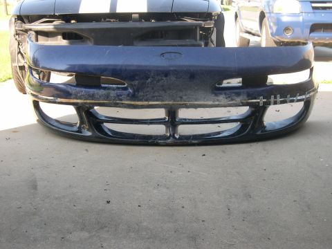 1997 Ford Probe - Front bumper of a blue vehicle, with racing stripes visible on the hood. Another vehicle is parked behind.