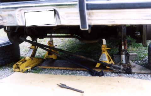 1979 Ford Bronco - The underside of a vehicle is supported by jack stands while undergoing maintenance.