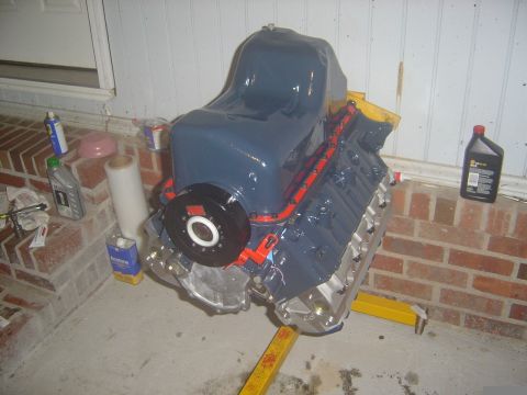 1986 Ford Bronco - Engine assembly on a stand, with various automotive fluids and supplies nearby.