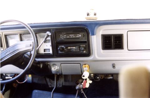 1979 Ford Bronco - The dashboard of a vehicle shows the steering wheel, instrument cluster, and dual DIN radio setup.
