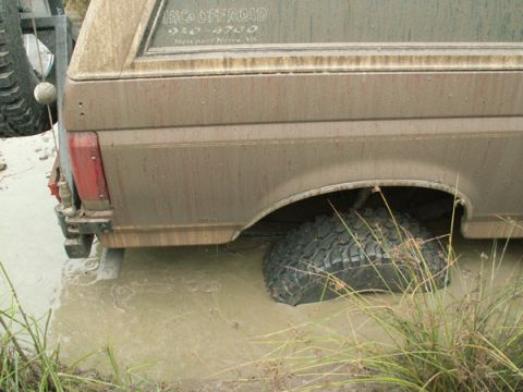 1988 Ford Bronco - Muddy 1988 Ford Bronco stuck in water, showing rear wheel submerged.