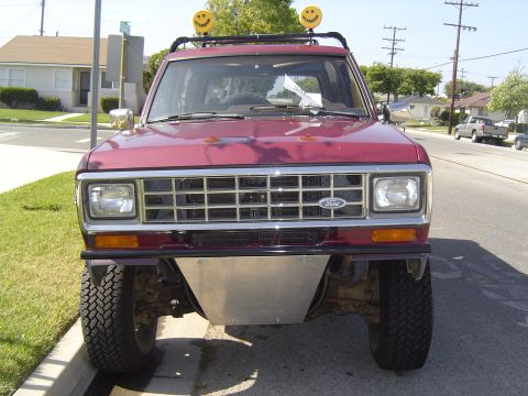 1985 Ford Bronco II - Front view of a maroon Ford Bronco II with a custom skid plate and roof-mounted smiley face lights.