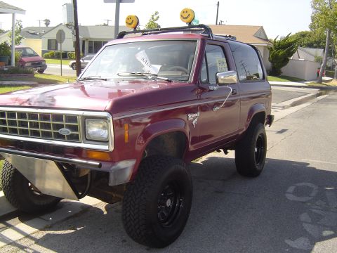 1985 Ford Bronco II - Maroon 1985 Ford Bronco II parked on a street, smiley face lights on the roof rack.