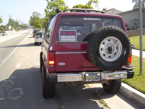 1985 Ford Bronco II - This red Ford Bronco II is parked on the side of a suburban street with a 'For Sale' sign in the window.