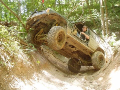 1992 Ford Bronco - A driver navigates a challenging off-road trail in a heavily modified 1992 Ford Bronco.