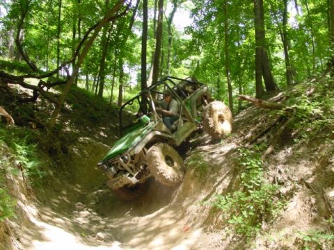 1992 Ford Bronco - Off-road buggy navigates a challenging dirt trail through a wooded area.