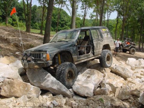1992 Ford Bronco - Modified Jeep Cherokee XJ navigates a rocky trail, with another off-road vehicle following.