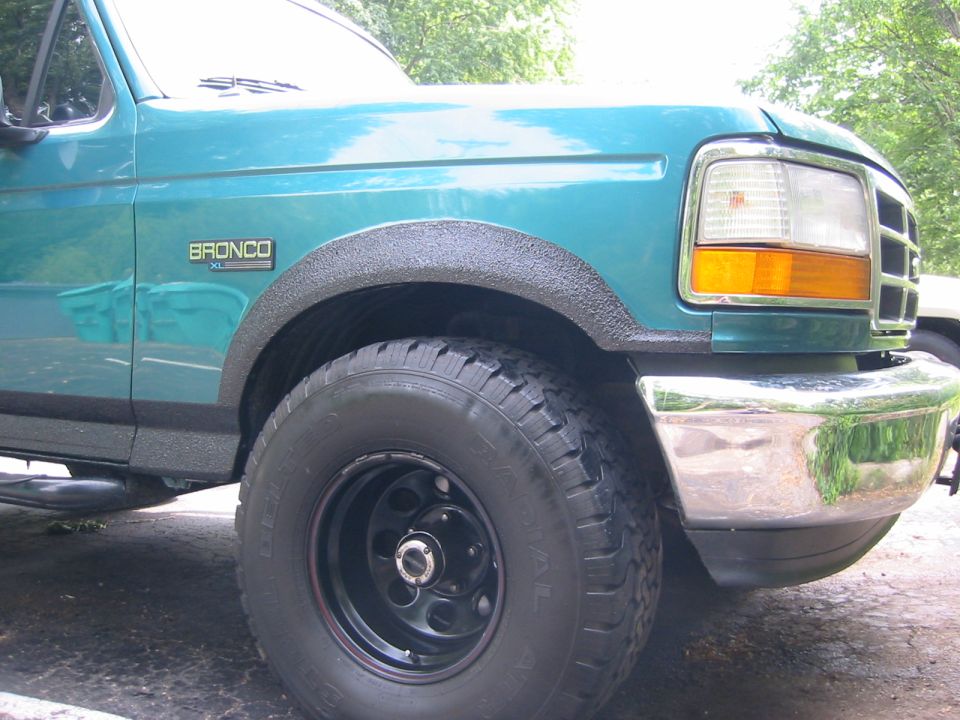 Teal Ford Bronco front fender with black bedliner-coated wheel arch and steel wheel