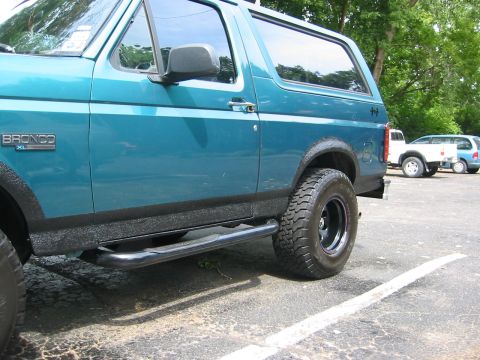 1996 Ford Bronco - Low side view of a teal Ford Bronco XL 4x4 with fresh black bedliner-textured coating applied along the lower rocker panels, fender flares…