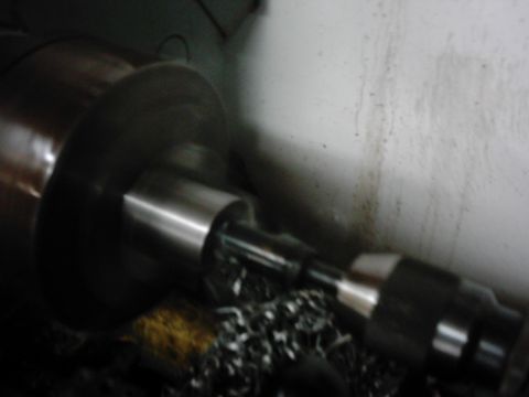 1978 Ford Bronco - A metal shaft is being machined on a lathe, creating metal shavings. The Supermotors.net logo is visible.