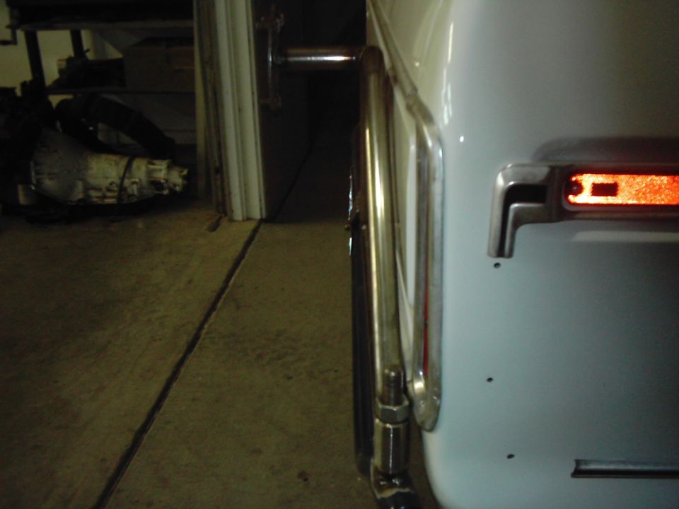Close-up of a spare tire carrier mounted on the rear of a vehicle, showing a chrome trim piece and an amber reflector