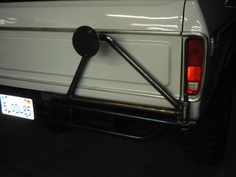 1978 Ford Bronco - Rear view of a white SUV's tailgate, showing a custom spare tire carrier and a license plate.