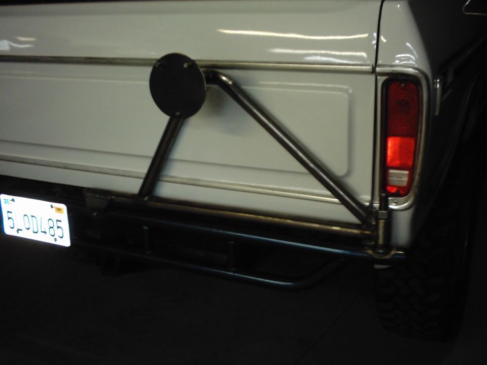 White SUV tailgate with custom metal spare tire carrier, California license plate 5.0DL85, and red taillight
