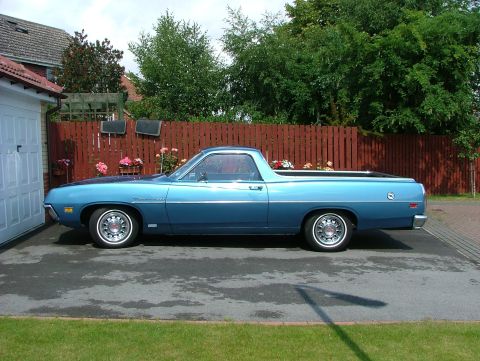 1970 Ford Ranchero - A blue 1970 Ford Ranchero is parked on a paved driveway next to a garage.