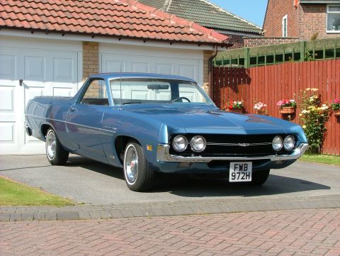 1970 Ford Ranchero - A light blue coupe utility with quad round headlights and a chrome front bumper sits on a brick driveway in front of a white double garage,…