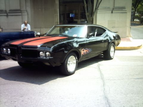 1995 Ford Probe - A black muscle car with orange racing stripes and flame decals is parked on a street.