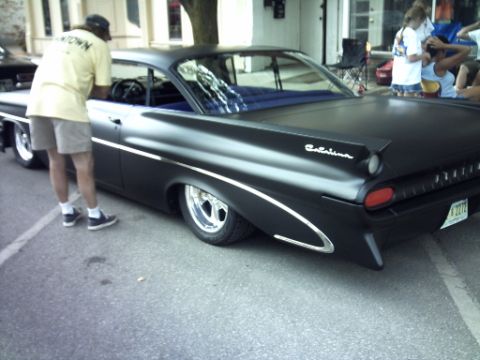 1995 Ford Probe - A black 1950s sedan, possibly a Catalina, is shown from the rear at an outdoor event.