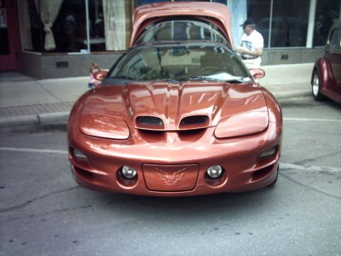 1995 Ford Probe - Orange Pontiac Firebird with hood open, parked on a street next to another vehicle.