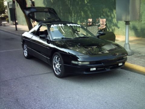 1995 Ford Probe - A black 1995 Ford Probe is parked on the street with its trunk open.