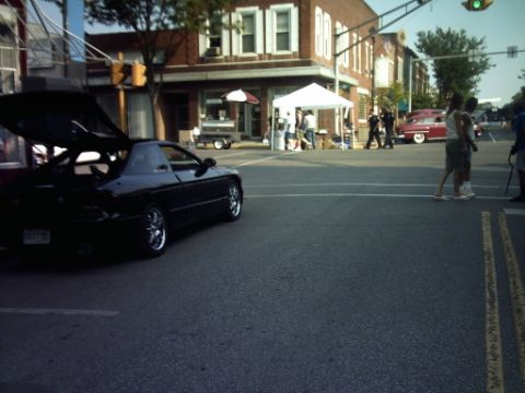 1995 Ford Probe - A black coupe with its trunk open is parked on a street, with a red classic car visible in the background.