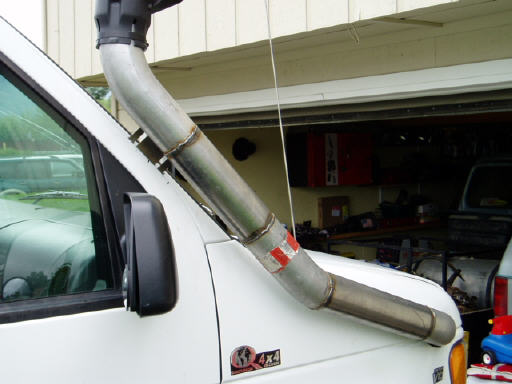 Bare metal snorkel intake routed up A-pillar of white van, garage behind