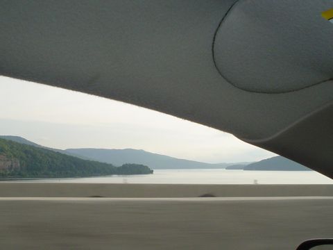 1981 Ford Bronco - View from inside a vehicle shows a lake surrounded by tree-covered mountains under a cloudy sky.