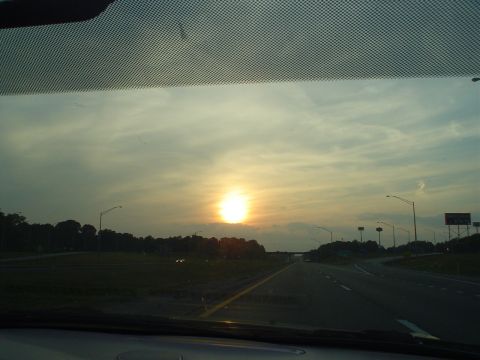 1981 Ford Bronco - View from inside a car on a highway as the sun sets, with streetlights visible.